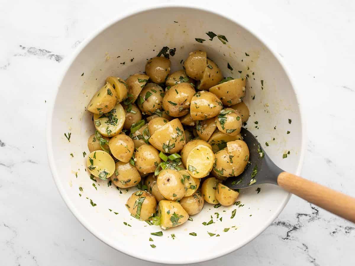 Herbs added to the potato salad in the bowl.