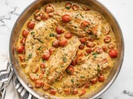 Overhead view of a skillet full of creamy pesto chicken.