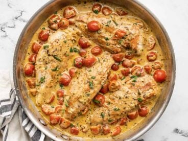 Overhead view of a skillet full of creamy pesto chicken.