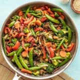 Vegetable stir fry in the skillet against a blue background.