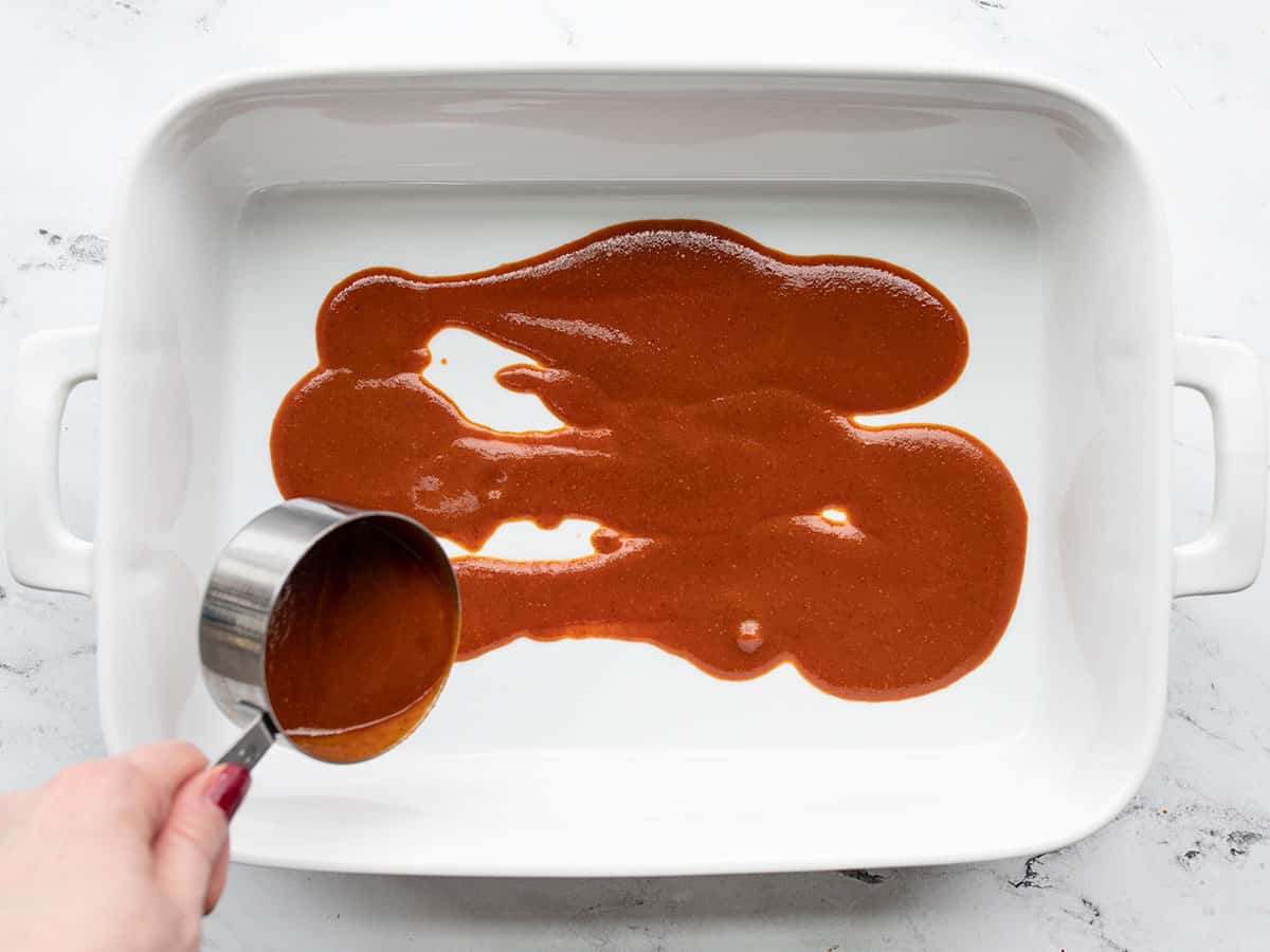 Enchilada sauce in the bottom of a casserole dish.