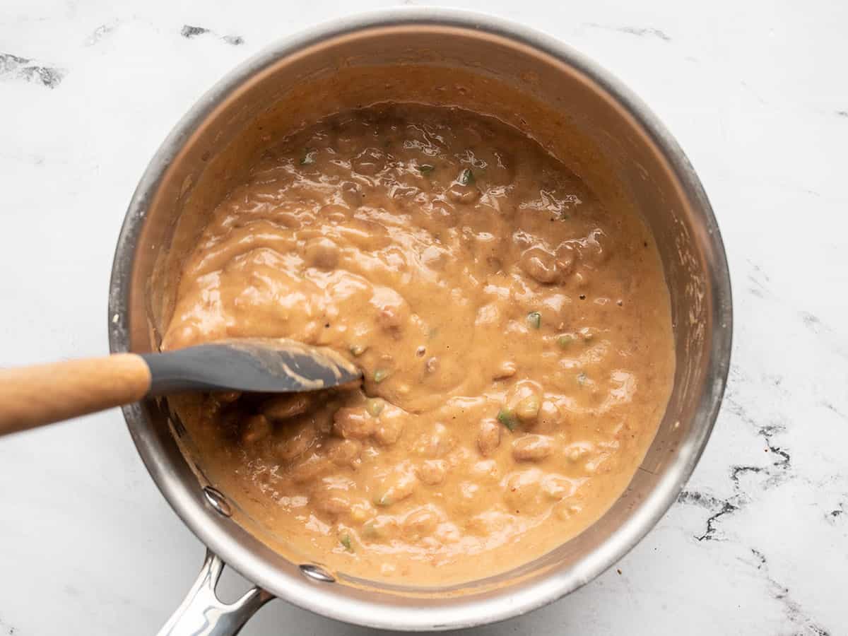 Cheesy pinto beans being stirred.