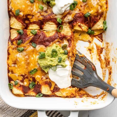 Close up of enchiladas being scooped out of the casserole dish