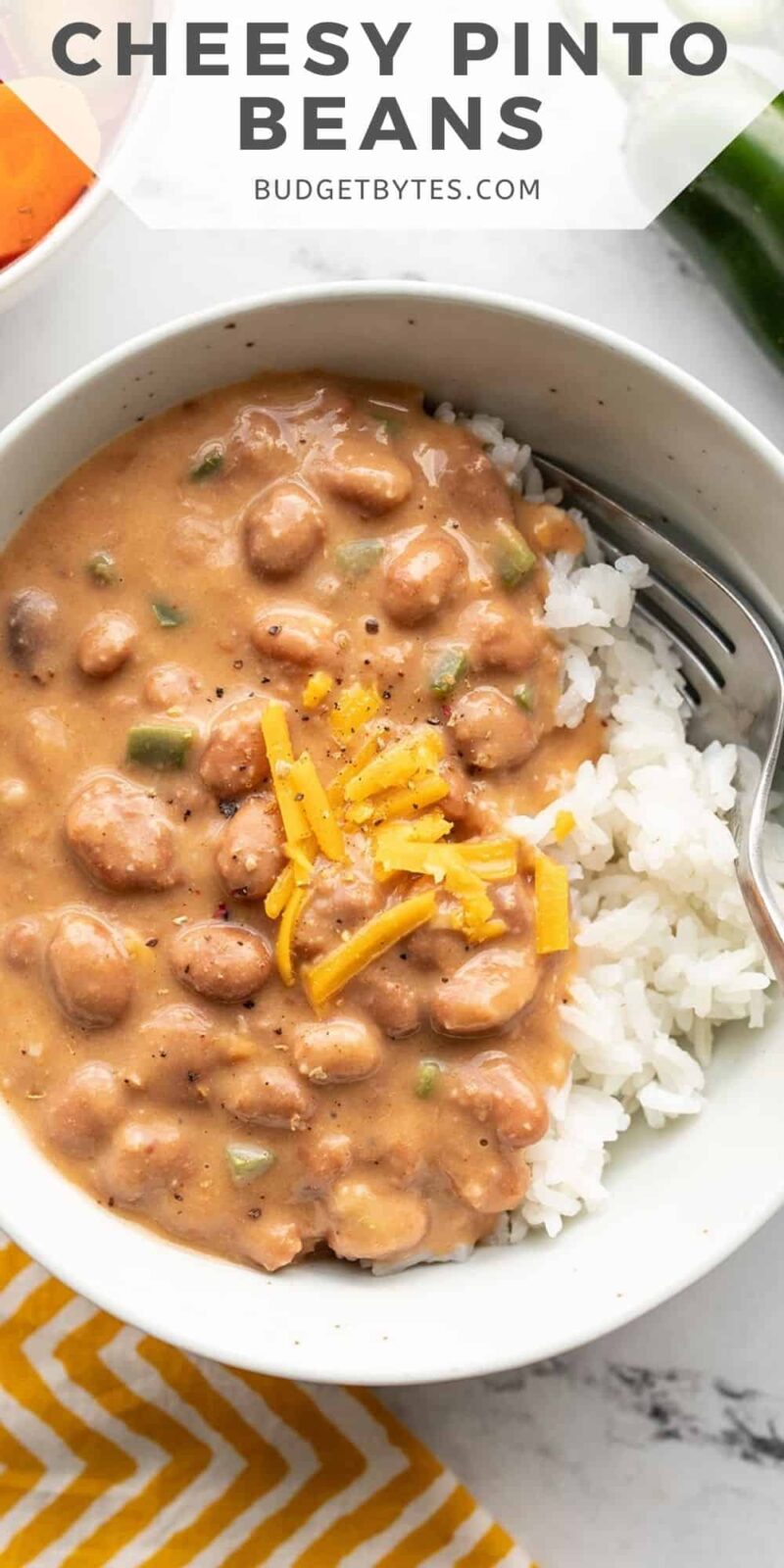 Close up overhead view of a bowl of cheesy pinto beans with rice.