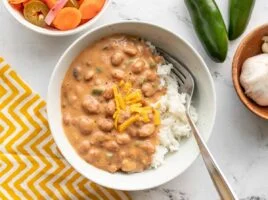 Overhead view of a bowl of cheesy pinto beans over rice.