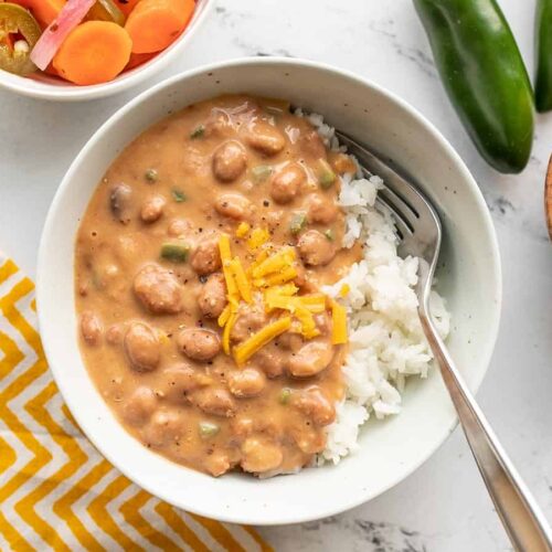 Overhead view of a bowl of cheesy pinto beans over rice.