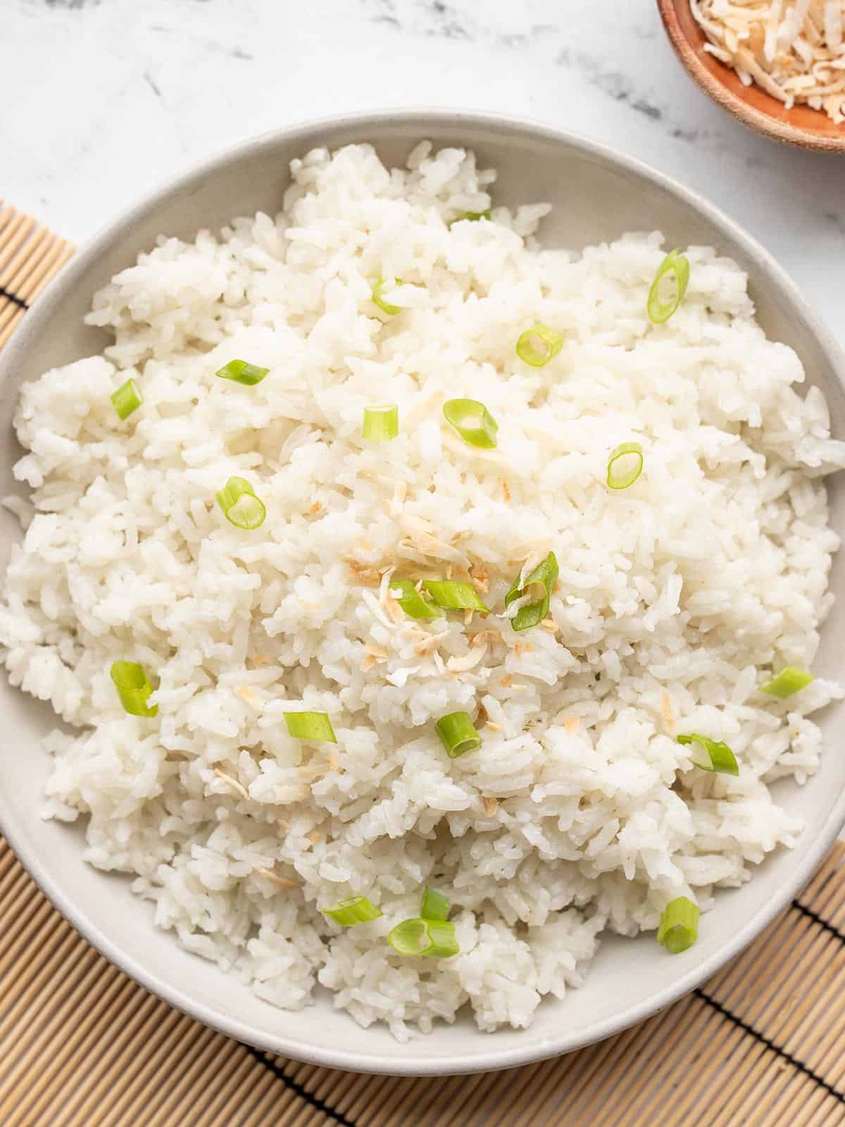 Overhead view of a plate full of coconut rice on a bamboo mat.