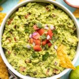 close up of guacamole in the bowl with a chip.