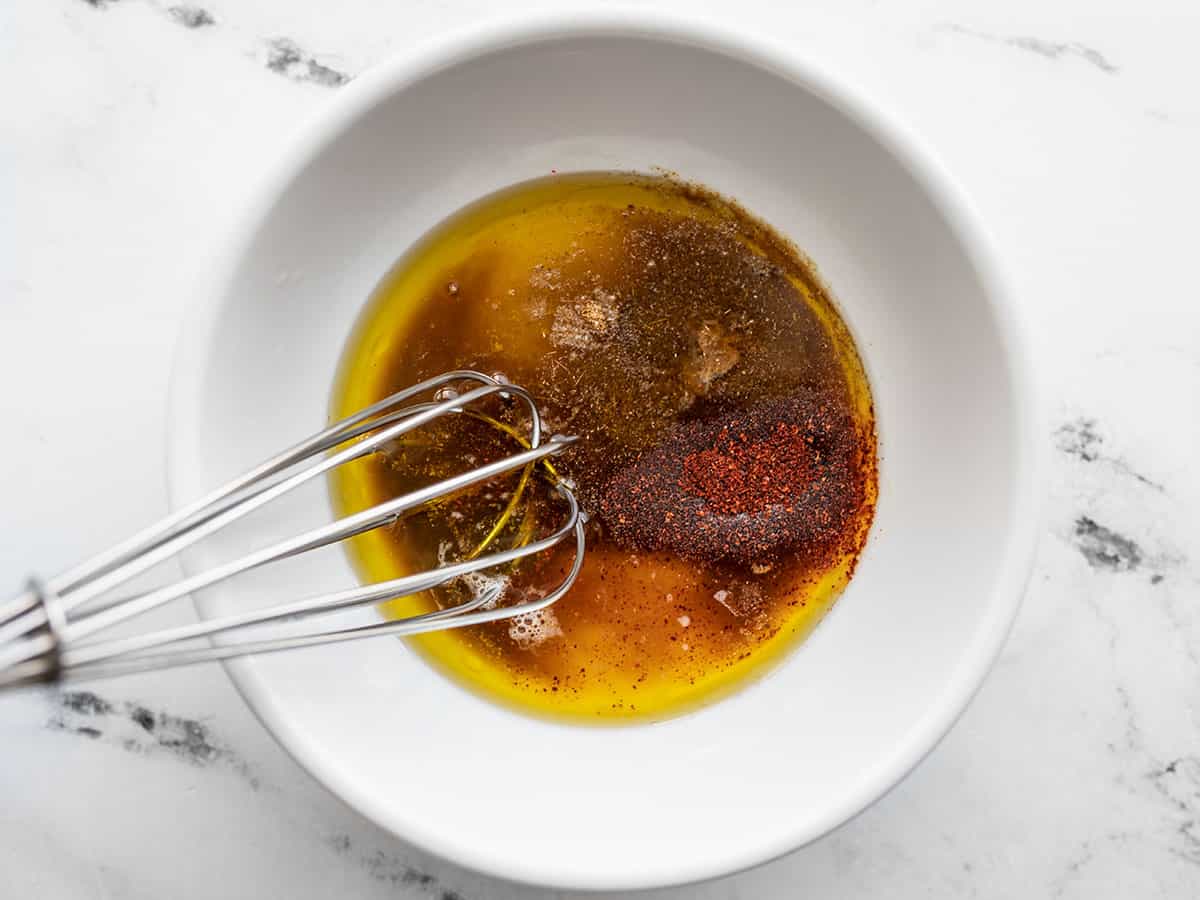 Dressing ingredients in a bowl with a whisk.