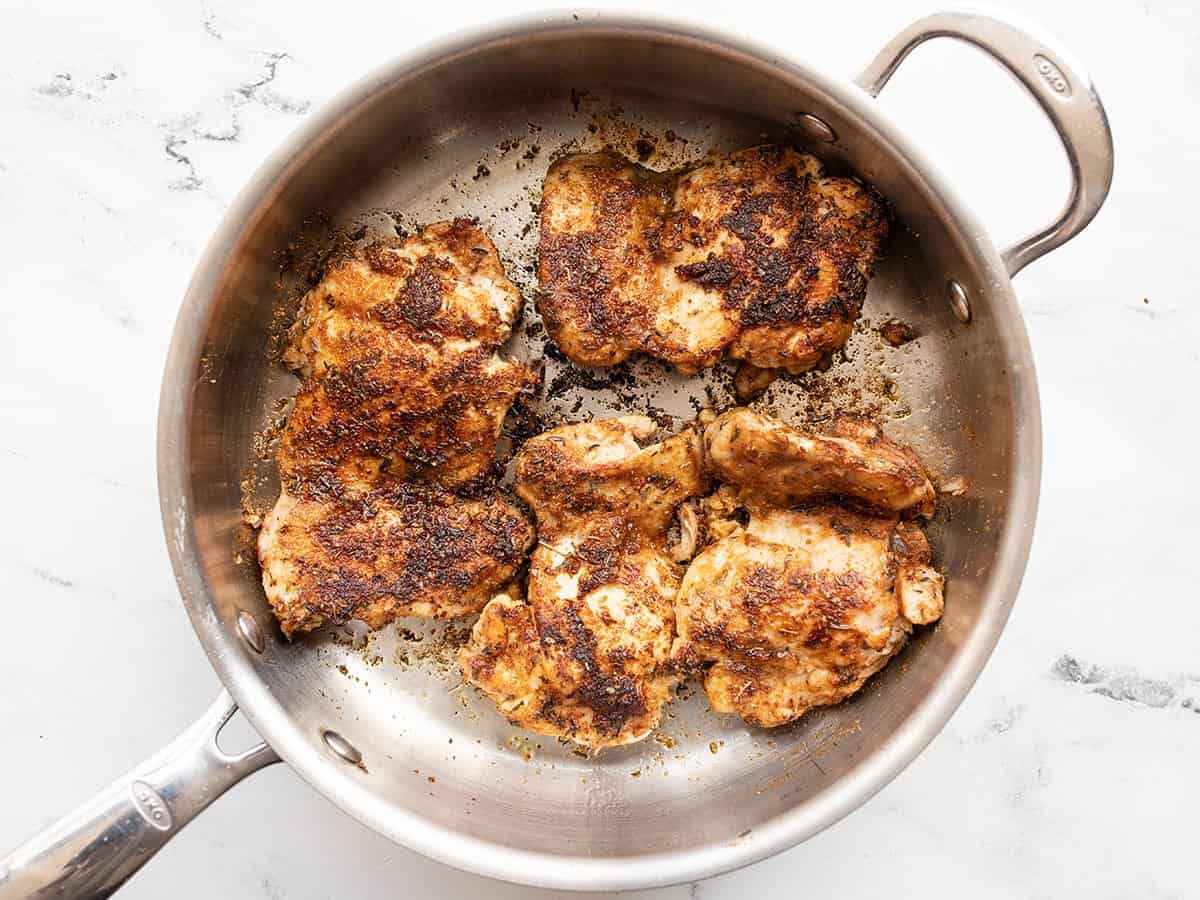 Browned chicken thighs in the skillet.