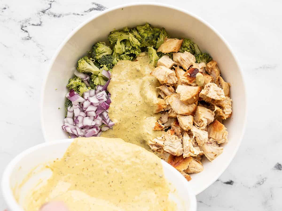 Pesto dressing being poured over the salad.