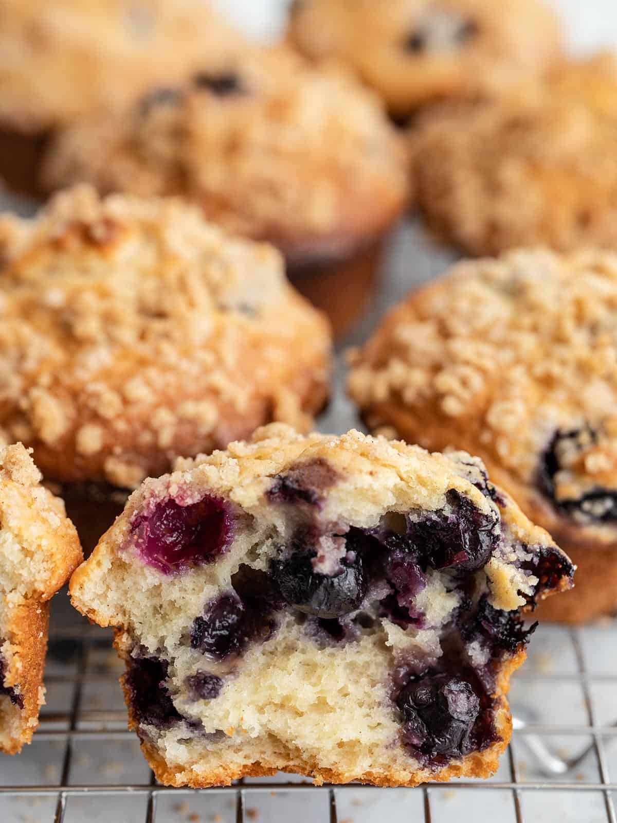 Blueberry muffins on a cooling rack with the first one torn open.