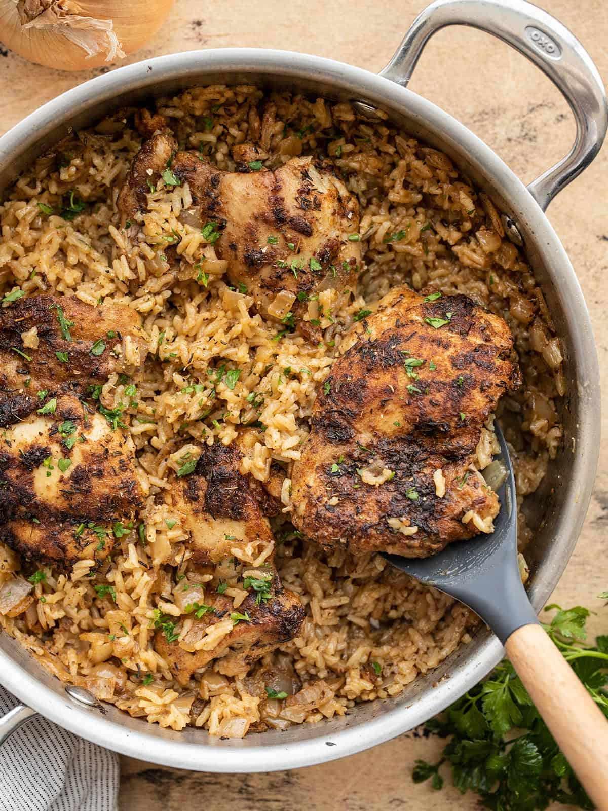 chicken and rice being scooped out of the skillet.