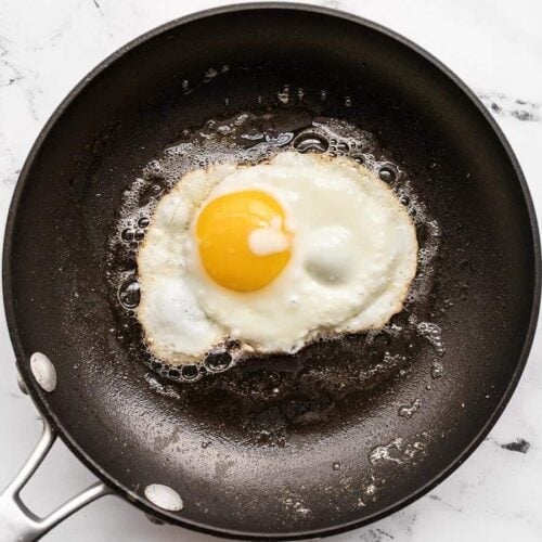 Frying an egg in a skillet on a stovetop.