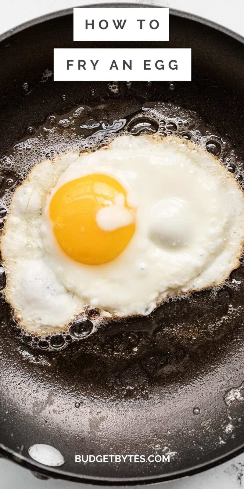 Close up overhead view of an egg frying in a pan.