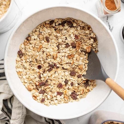 Overhead view of a bowl full of muesli with ingredients on the sides.