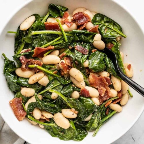 Close up overhead view of a bowl of wilted spinach salad.