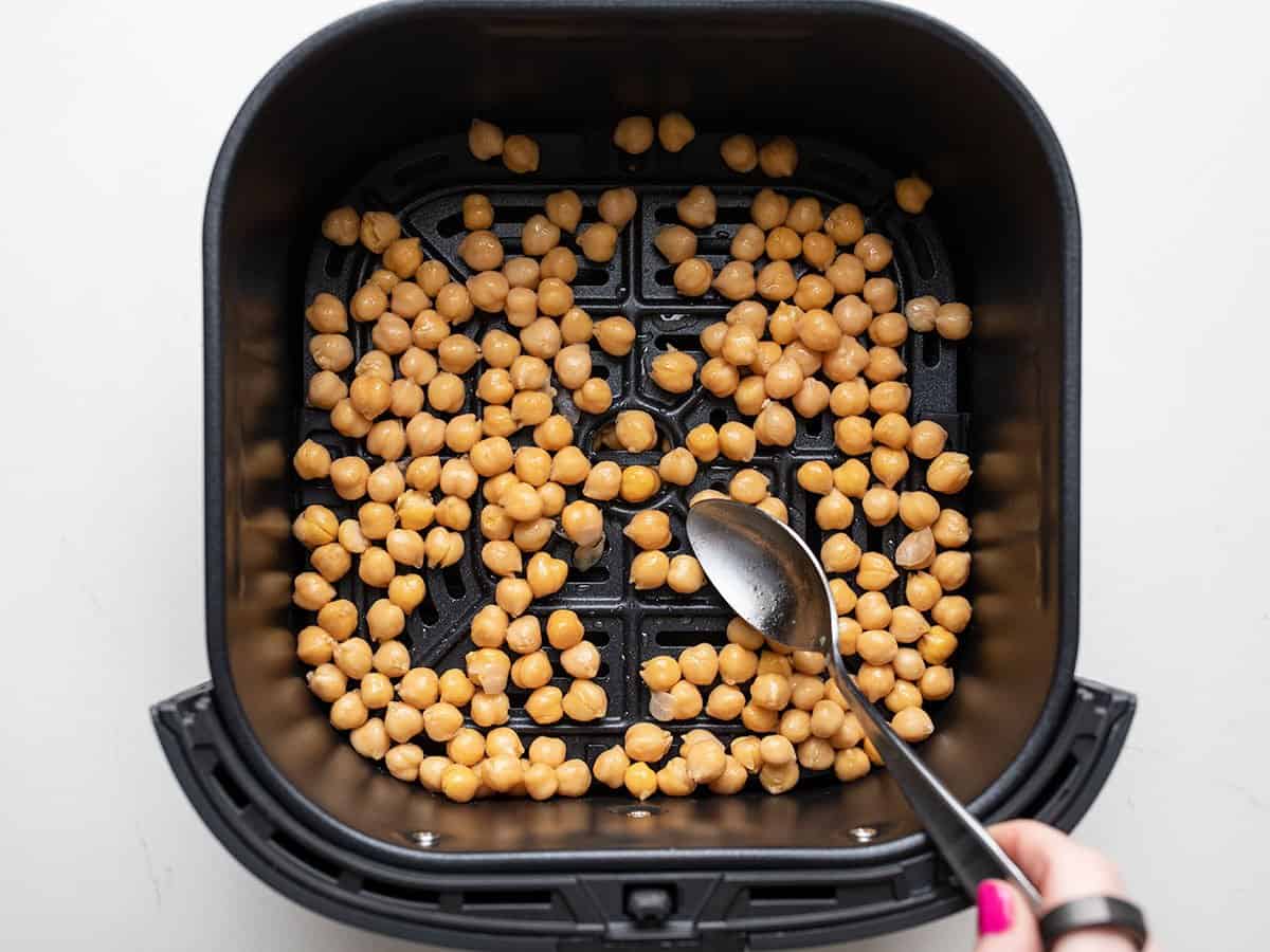 Uncooked chickpeas in air fryer basket.