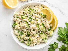 Overhead view of lemony cucumber couscous salad in a bowl garnished with lemons.