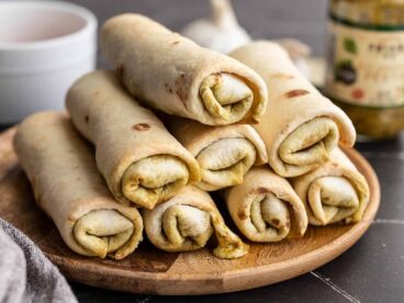 Side view of pesto mozzarella roll ups stacked on a plate.