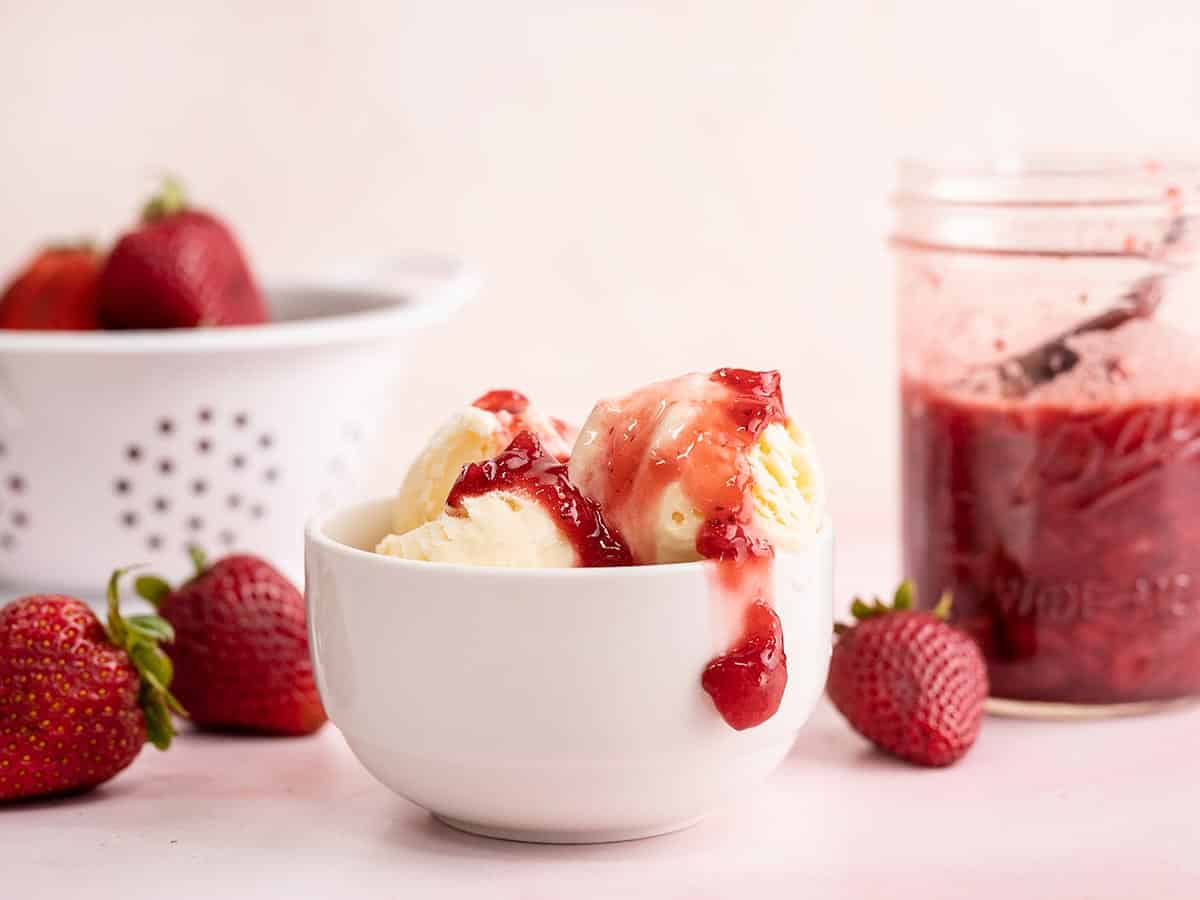 A bowl of ice cream with strawberry syrup on top.