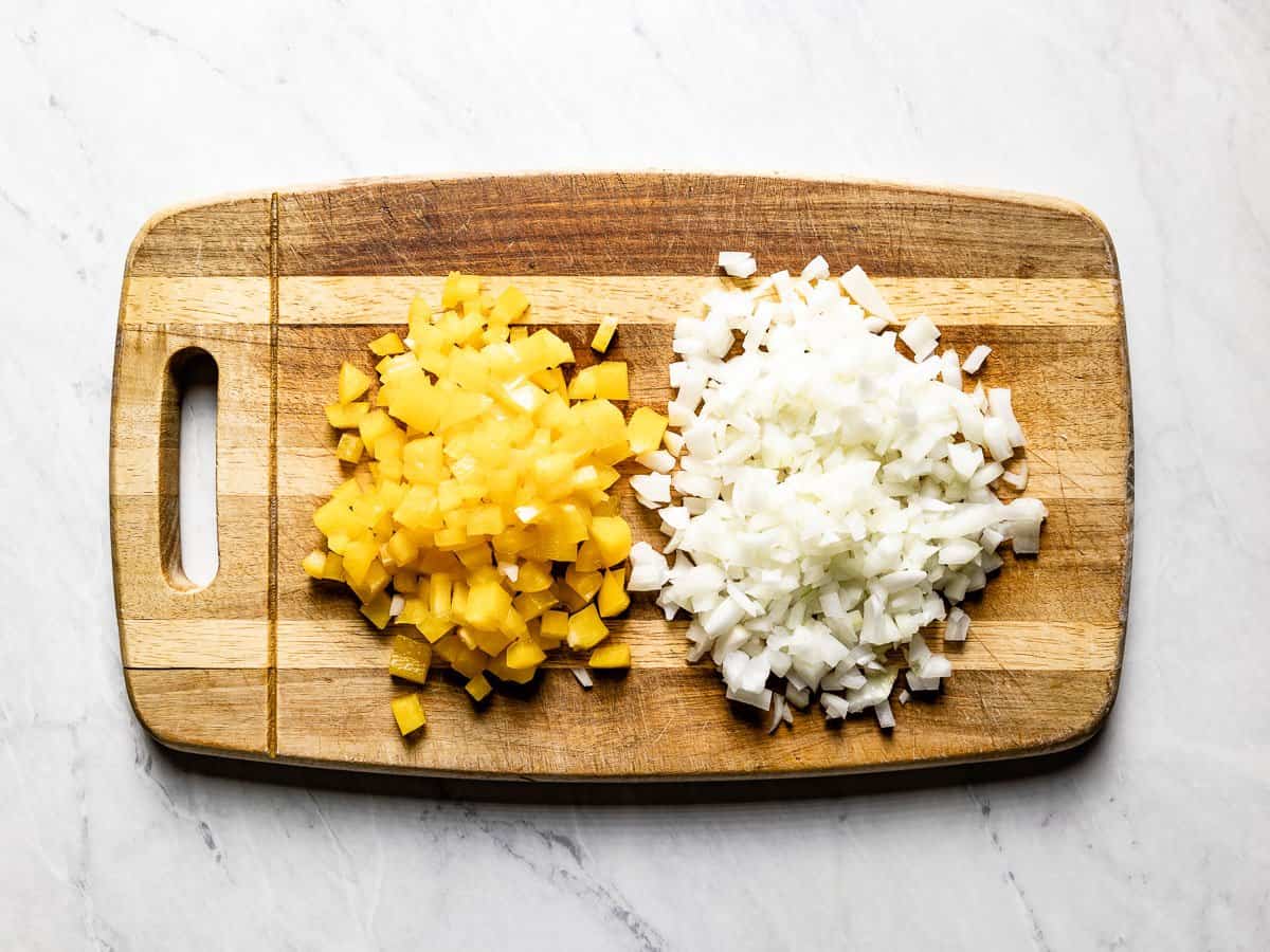 Diced onion and bell pepper on a cutting board.