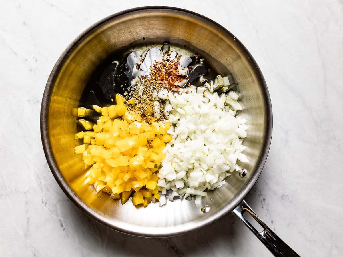 Onion, bell pepper, and spices in a skillet.