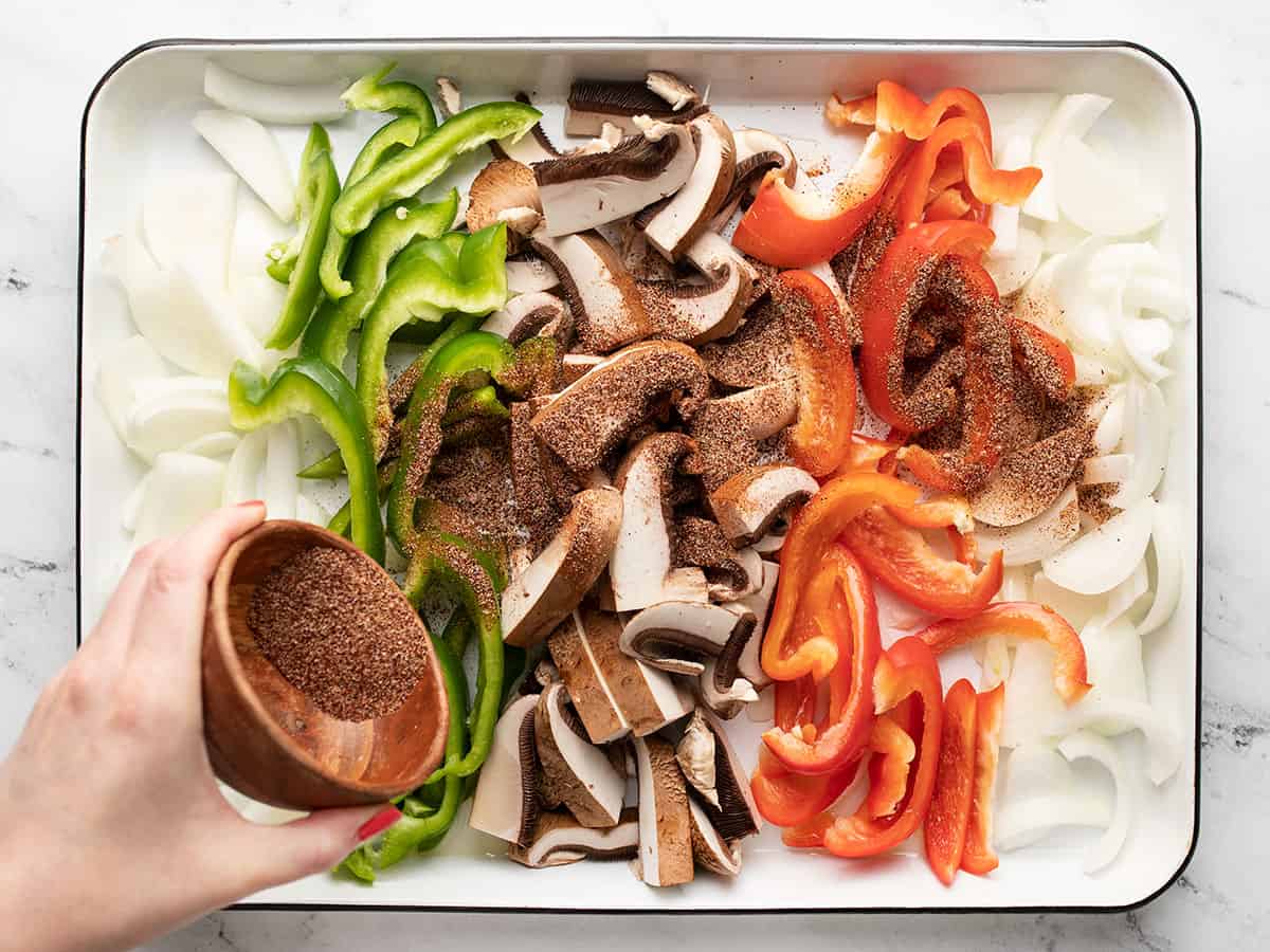 Spices being sprinkled over the sliced vegetables.