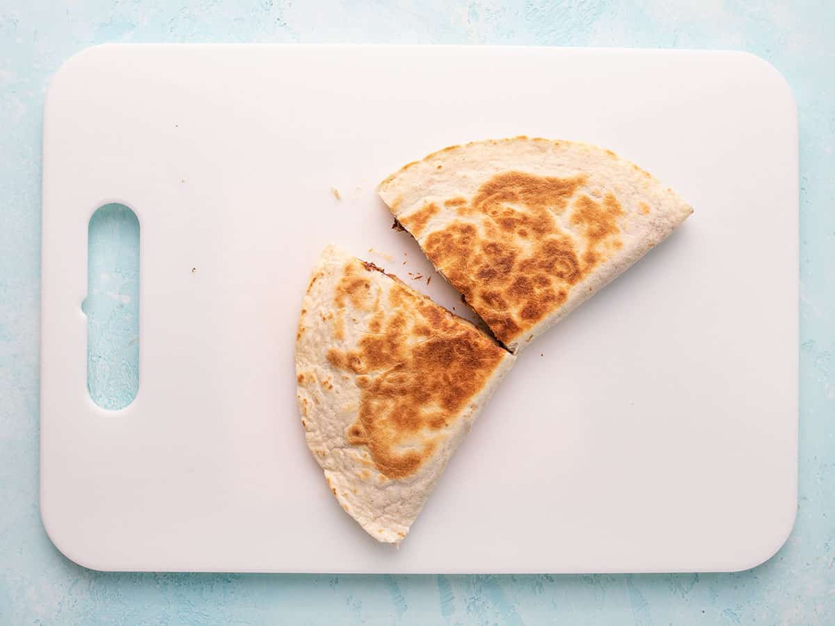 Quesadilla on a cutting board sliced in half.