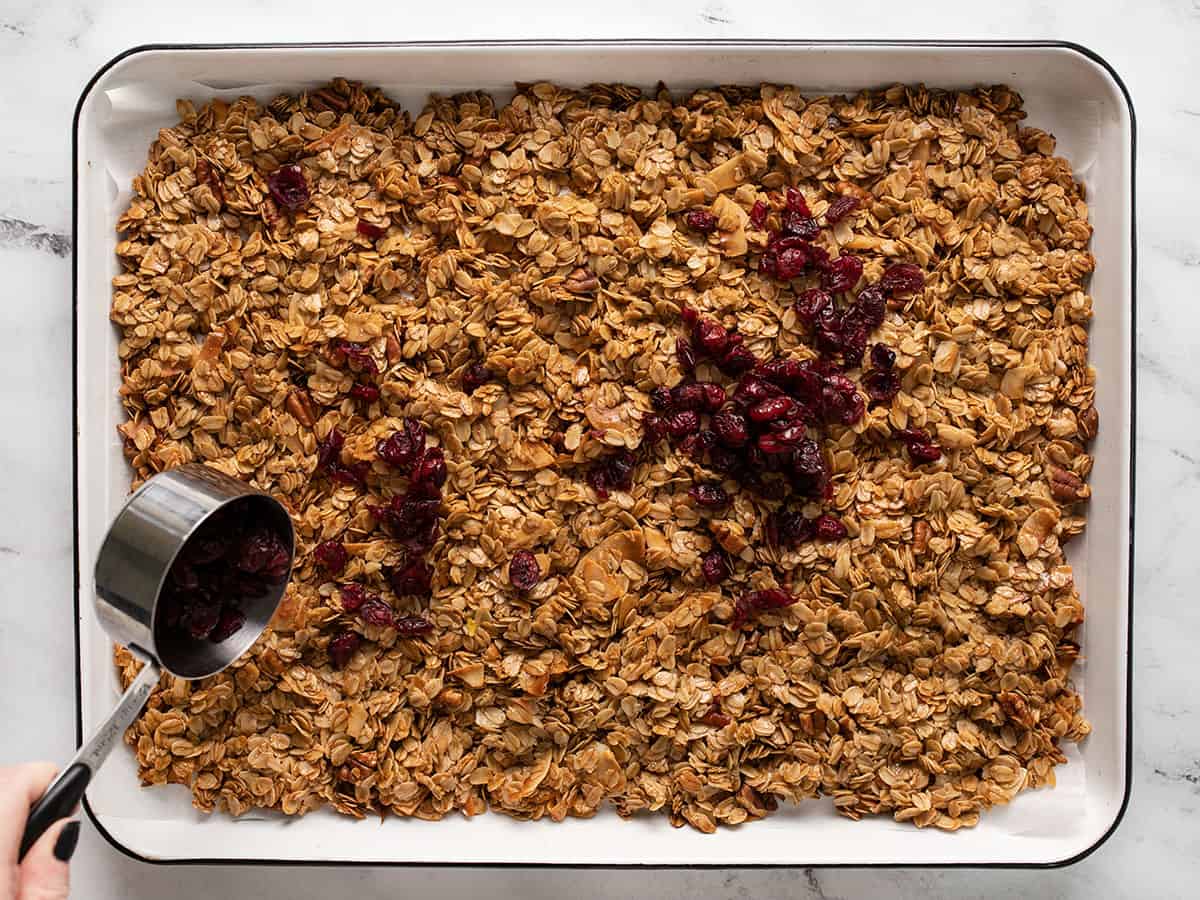 Dried cranberries being added to the granola after baking.