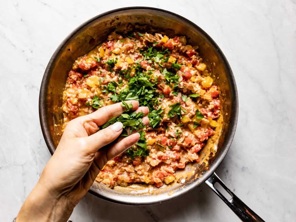 Parsley being sprinkled onto scrambled eggs.