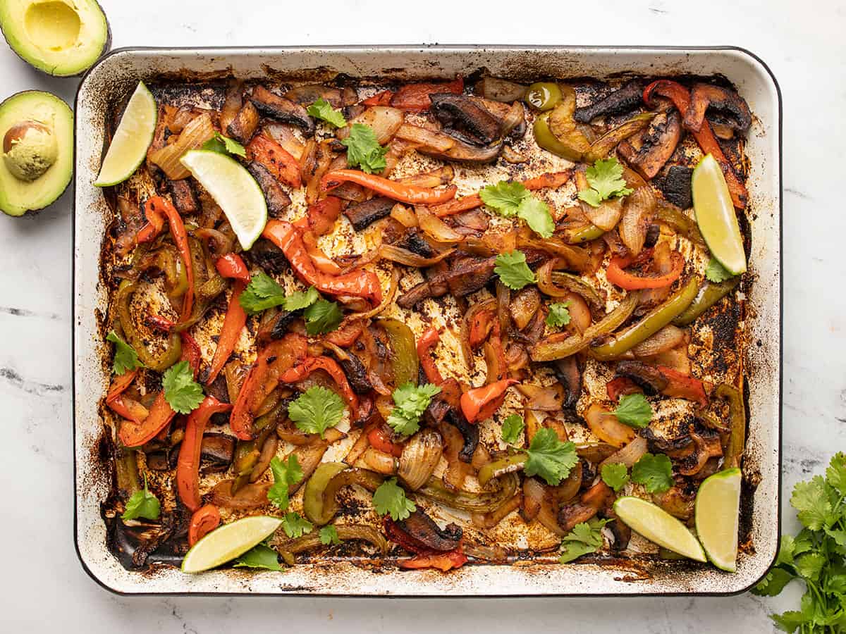 Finished fajita vegetables on the baking sheet with lime and cilantro.