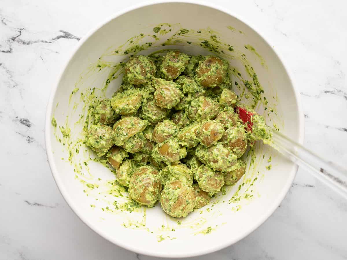 Finished parsley pesto potato salad in a bowl with a spatula.