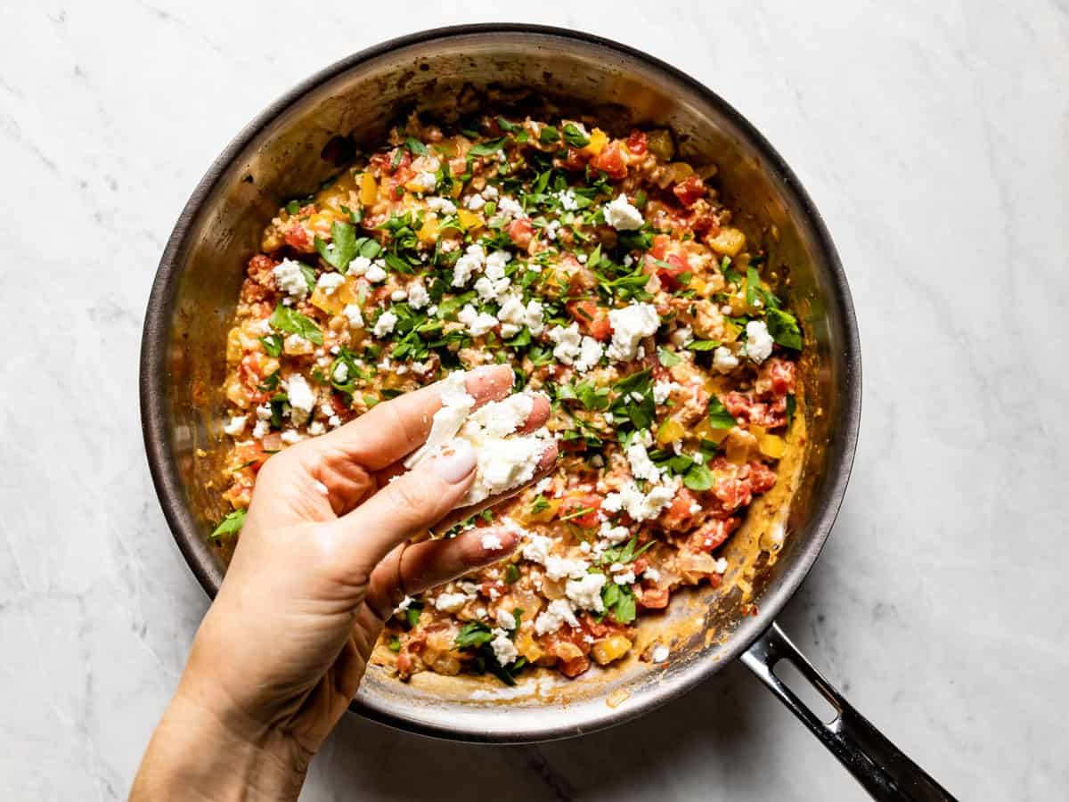 Feta being sprinkled over the eggs.