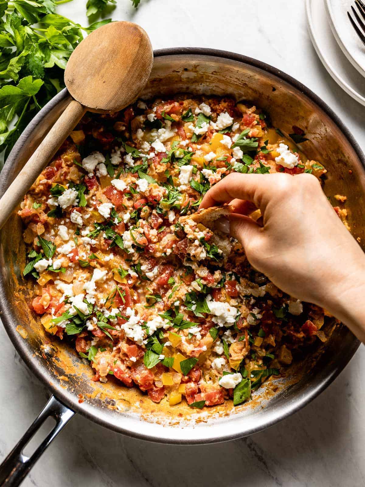 bread being dipped into a pan of menemen.