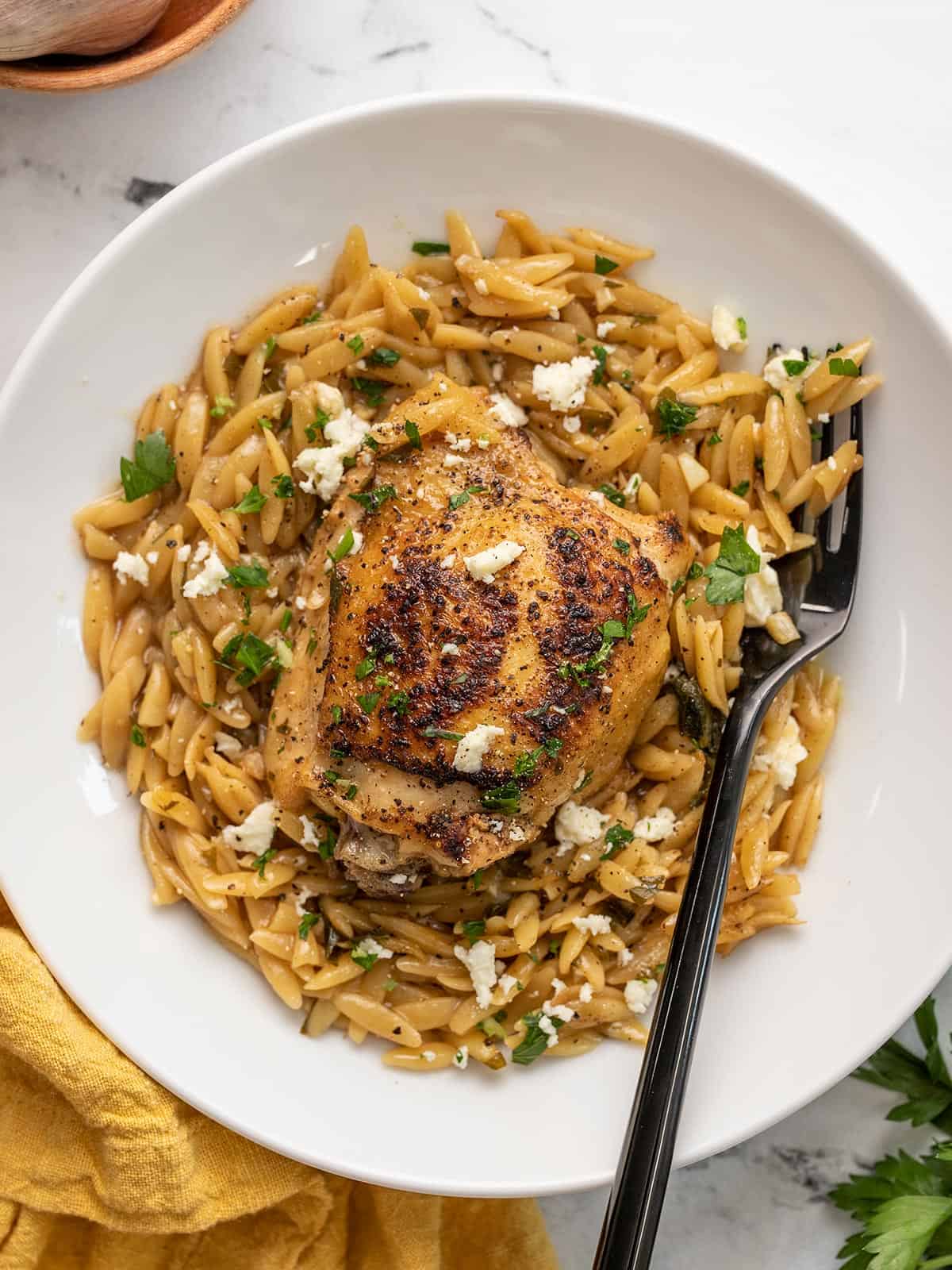 Overhead view of lemon pepper chicken and orzo in a bowl.