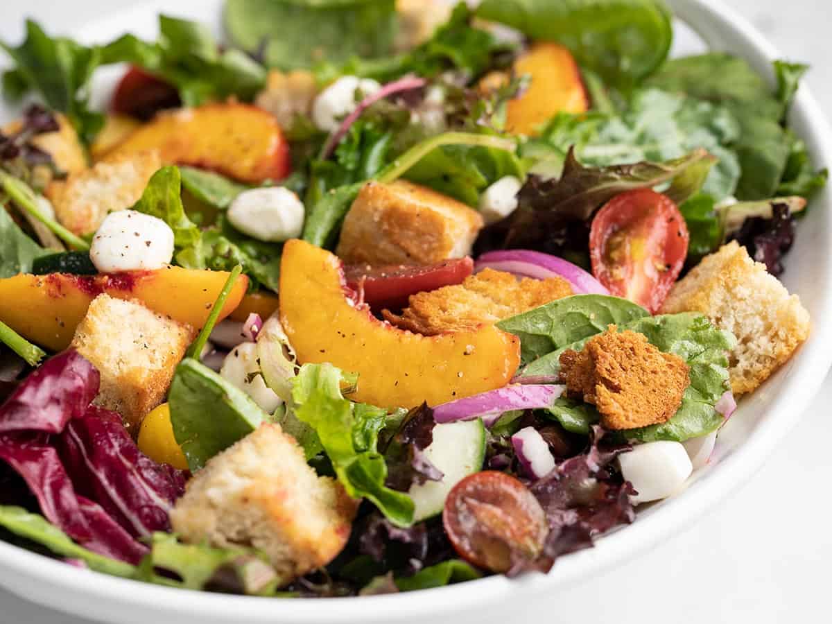 Side shot of panzanella salad in a white bowl.