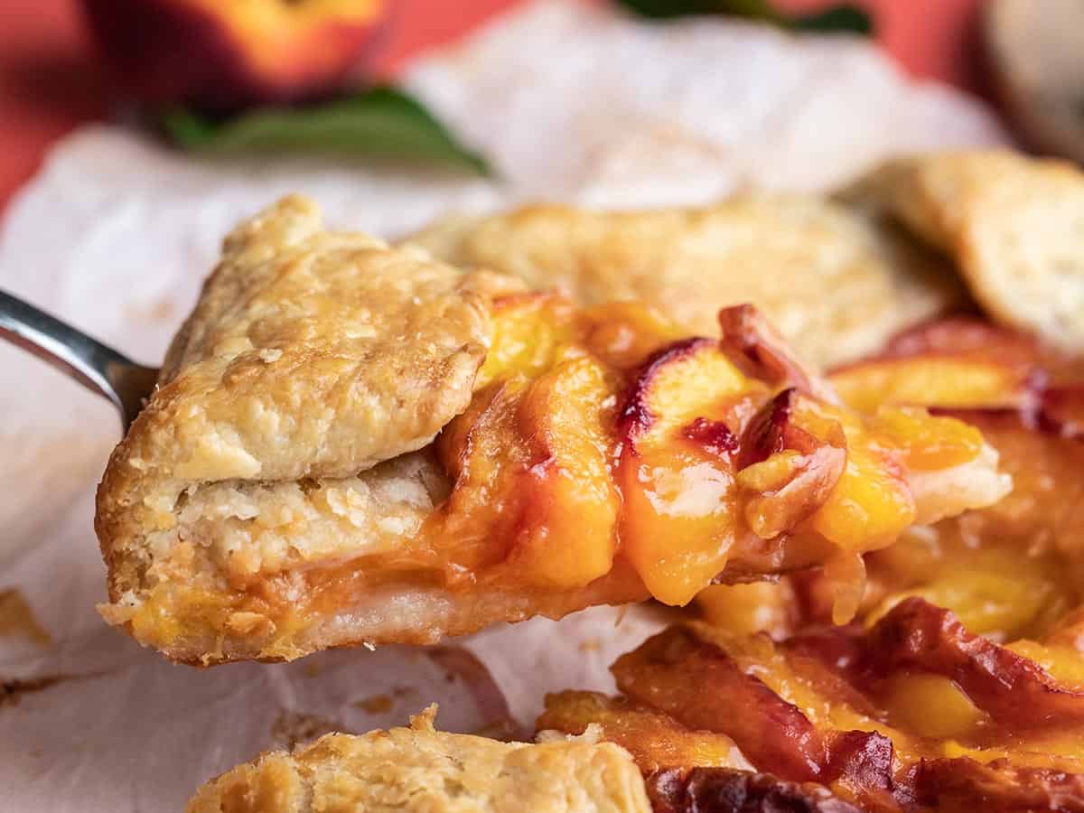 Side view shot of slice of peach galette being lifted by a pie spatula.