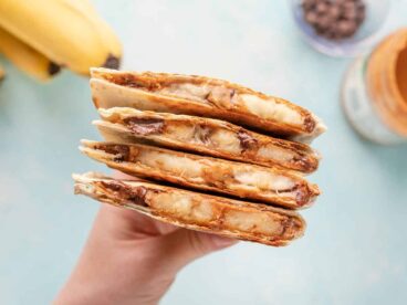 A hand holding a stack of peanut butter banana quesadillas.