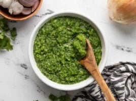 Overhead view of a bowl of sofrito with a wooden spoon.