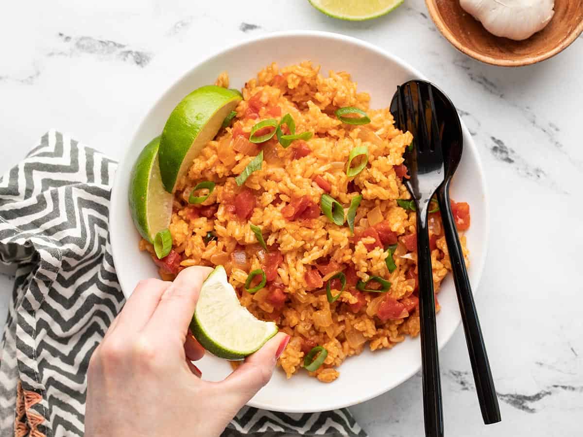 Lime being squeezed over the rice in a bowl.