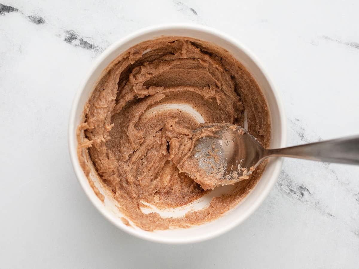 Overhead shot of spoon mixing cinnamon, butter, and sugar in a small bowl.