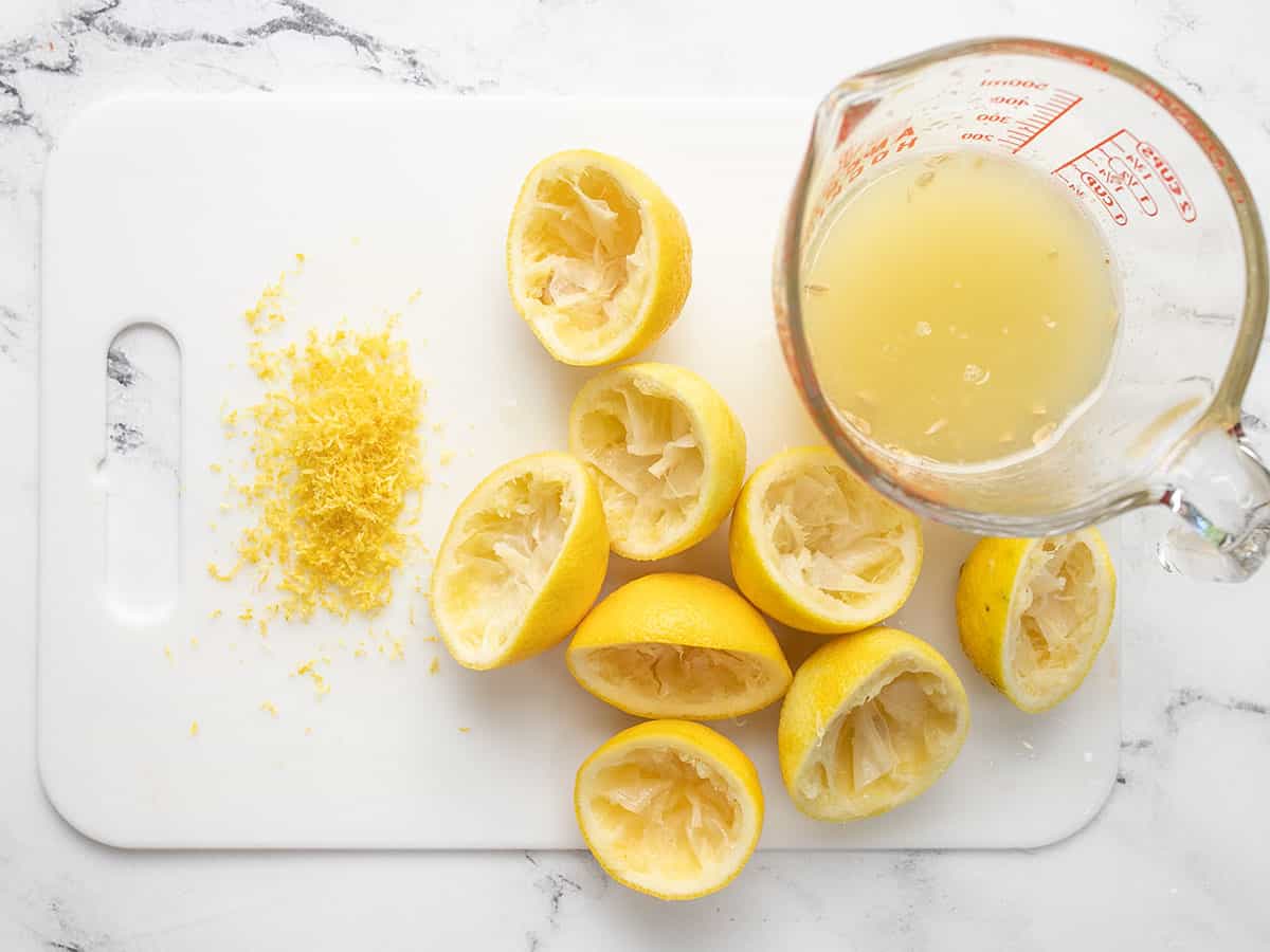 Juices and zested lemons on a cutting board.