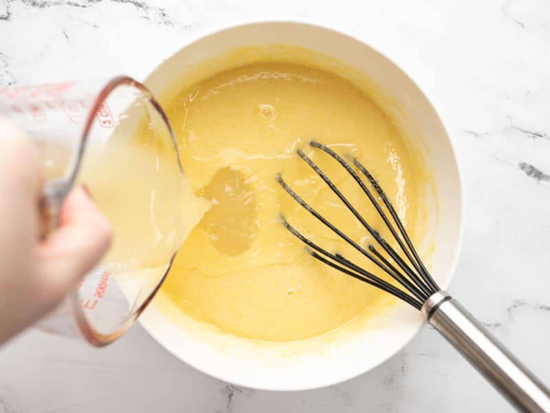 Juice being poured into the bowl with the custard ingredients.