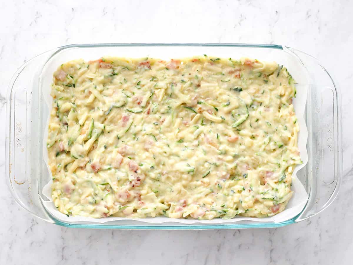 Unbaked zucchini slice in a glass casserole dish.