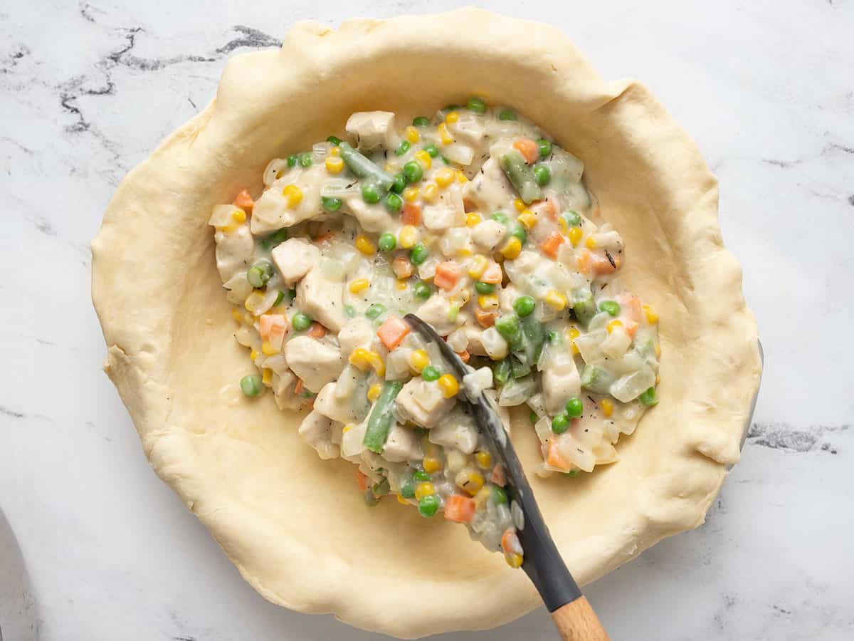 Pie filling being added to a pie crust.