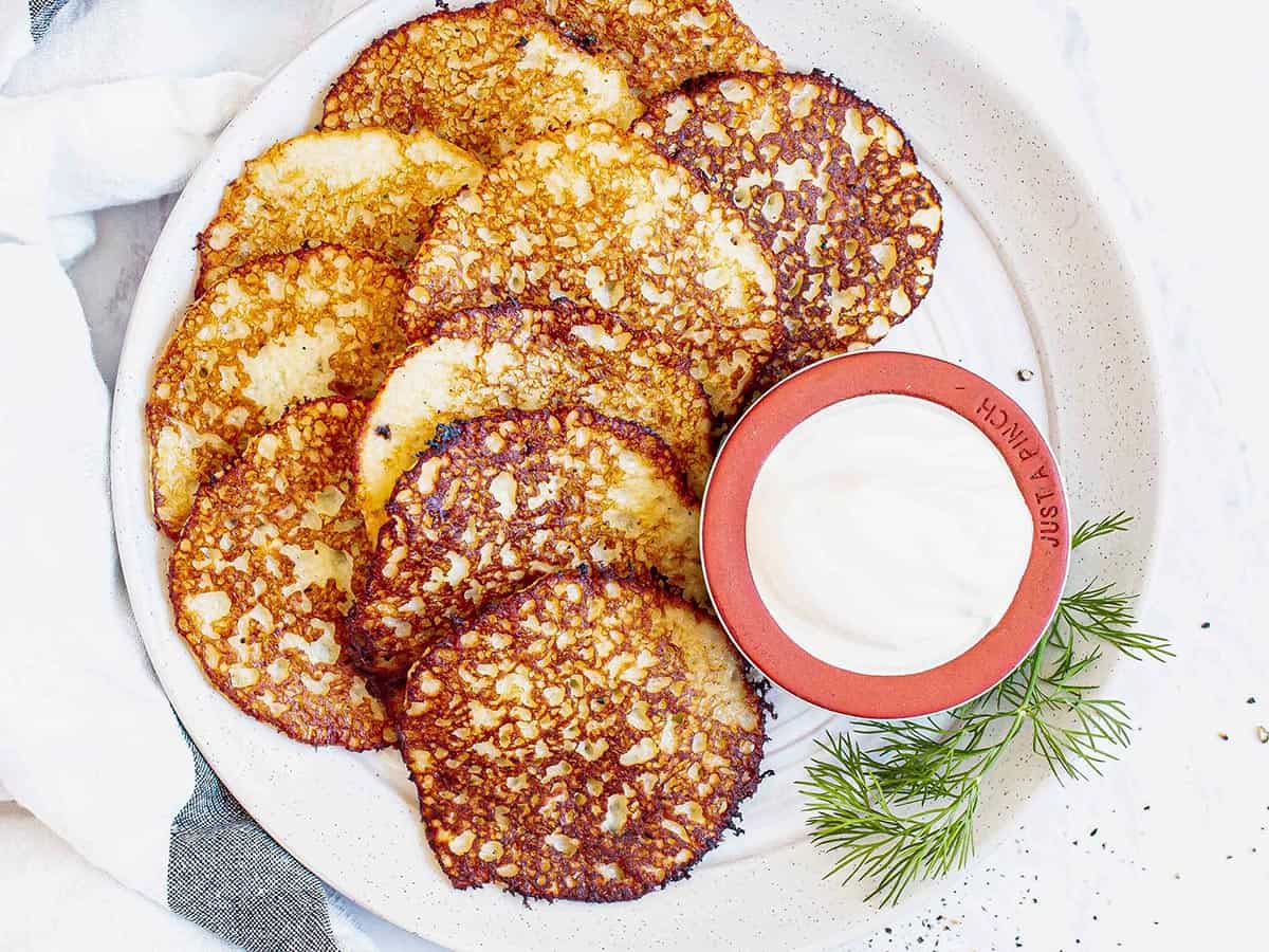 Overhead view of potato pancakes on a plate with sour cream.