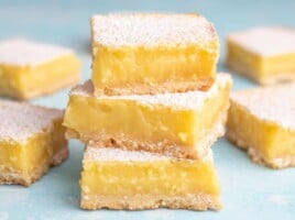 A stack of three lemon bars on a blue background.