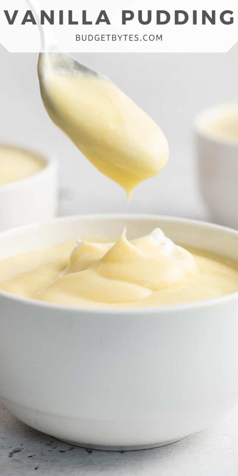 Side shot of vanilla pudding in a white bowl with a spoon coming out of it.