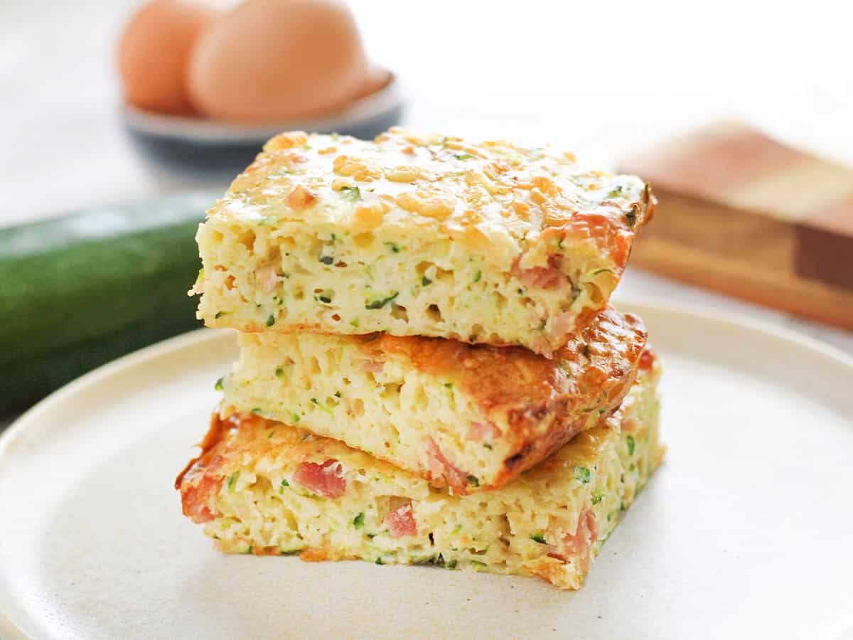 Three slices of zucchini slice stacked on a plate.